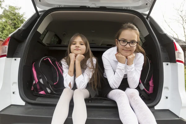 Portret van schattige schoolmeisjes poseren in open auto kofferbak — Stockfoto