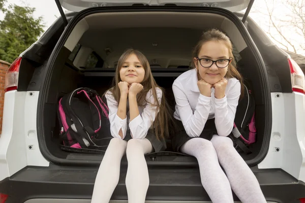 Portret van twee schattige meisjes zitten in open auto kofferbak — Stockfoto