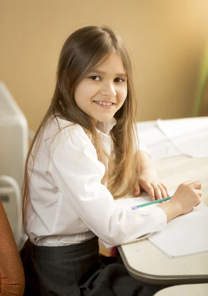 Chica alegre haciendo la tarea detrás del escritorio —  Fotos de Stock