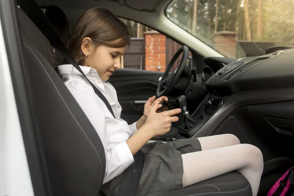 Portret van het meisje in de auto zitten en spelen op smartphone — Stockfoto