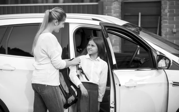 Retrato en blanco y negro de colegiala subiendo al coche y dando — Foto de Stock