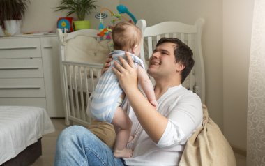 Çanta sandalyede oturan ve onun küçük bebek tutan genç Baba