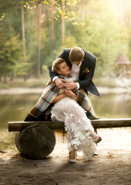 Ri, bankta oturmuş yakışıklı damat sarılma güzel gelin