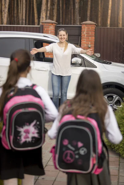 Two sisters with backpacks running to mother meeting them after — Stock Photo, Image