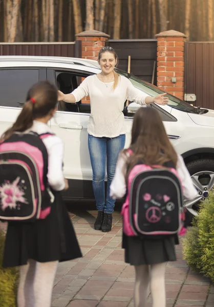 Весёлые девочки бегут к маме, встречая их после школы. — стоковое фото