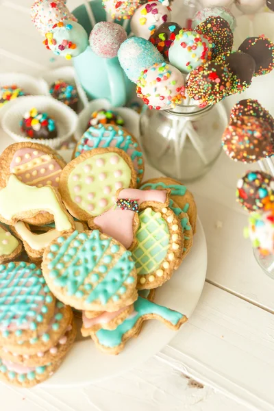 Colorful cake pops and cookies on white wooden desk — Stock Photo, Image