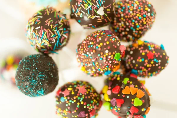 Toned photo of colorful sprinkles on chocolate cake pops — Stock Photo, Image