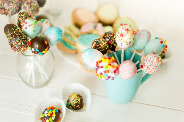 Closeup of colorful cake pops in cups on white wooden desk — Stock Photo, Image