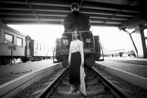 Photo en noir et blanc d'une femme posant sur des rails devant un rétro — Photo