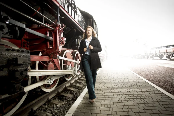 Tónovaný fotografie elegantní ženy chodit na železniční platforma minulosti o — Stock fotografie
