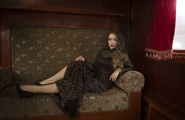 Mulher elegante em vestido vintage relaxante no sofá no quarto de hotel — Fotografia de Stock
