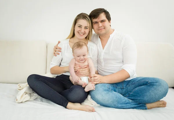 赤ちゃんの息子のベッドの上でポーズをとって幸せな若い家族 — ストック写真
