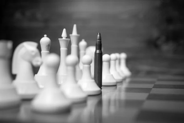 Foto conceptual en blanco y negro de la bala de rifa en el tablero de ajedrez —  Fotos de Stock