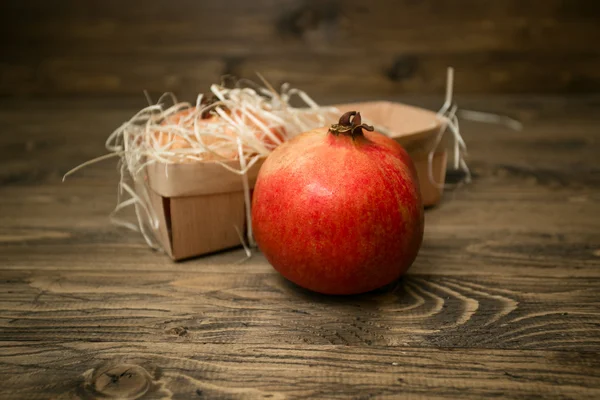 Frischer roter Granatapfel liegt auf Holzbrettern neben Korb — Stockfoto