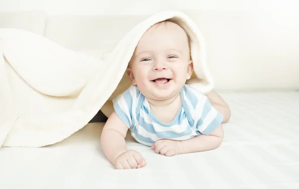 Aranyos nevető 6 hónapos kisfiú feküdt a takaró alatt — Stock Fotó