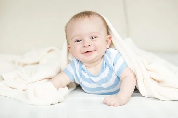 Glücklich kleines Baby kriecht auf Bett unter Decke — Stockfoto