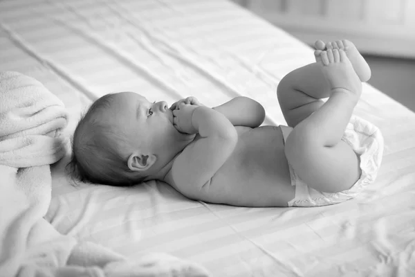 Svartvit bild på söta baby i blöjor liggande på sängen — Stockfoto