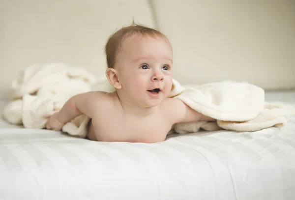 Retrato del niño sorprendido acostado debajo de una manta en la cama — Foto de Stock