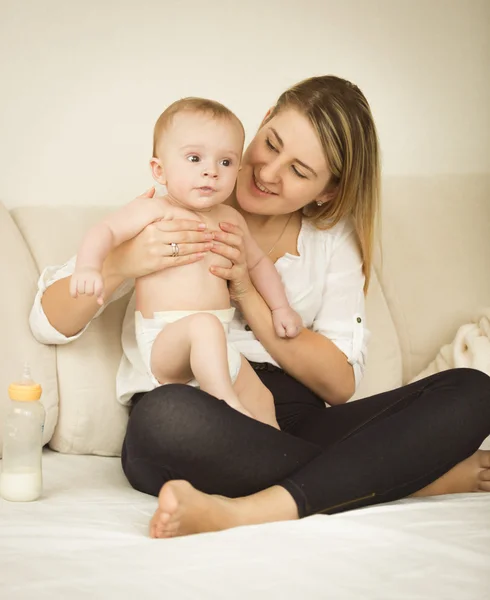 Allegro giovane madre in posa con il suo bambino di 6 mesi sul letto — Foto Stock