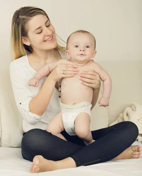 Foto tonificada de bebé de 6 meses relajándose en la cama con su madre — Foto de Stock