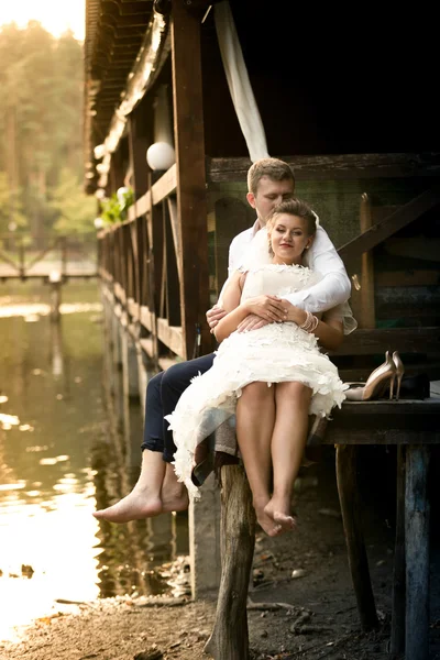 Happy newly married couple relaxing on pier at forest — Stock Photo, Image
