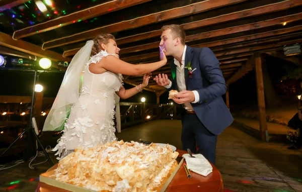 Retrato engraçado de noiva alimentando noivo com bolo de casamento — Fotografia de Stock