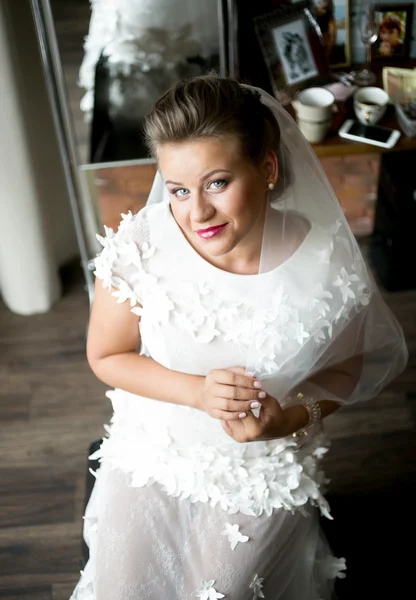Elegante lächelnde Braut posiert auf Stuhl vor Spiegel — Stockfoto