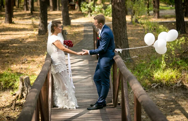 Pareja recién casada posando en un viejo puente de madera con ballo blanco — Foto de Stock