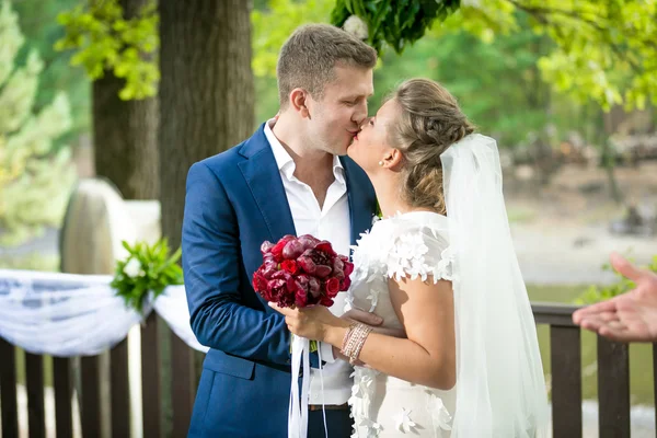 Mooie bruid en bruidegom met eerste kus op park — Stockfoto