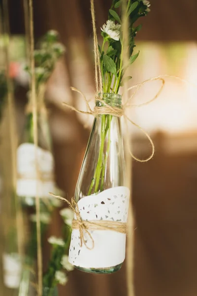 Närbild av dekorativa flaskor med blommor hängande på rep — Stockfoto