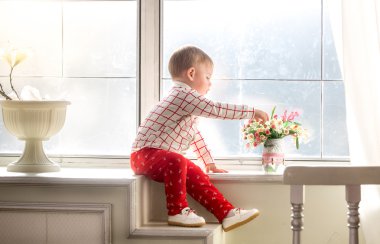 Pencere kenarında oturan ve güzel çiçek kokulu tatlı çocuk