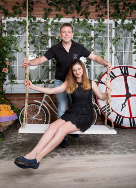 Yakışıklı adam kız arkadaşı stüdyoda salıncak üzerinde sallanan