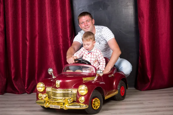 Bebê adorável sentado em grande carro de brinquedo e brincando com o pai — Fotografia de Stock