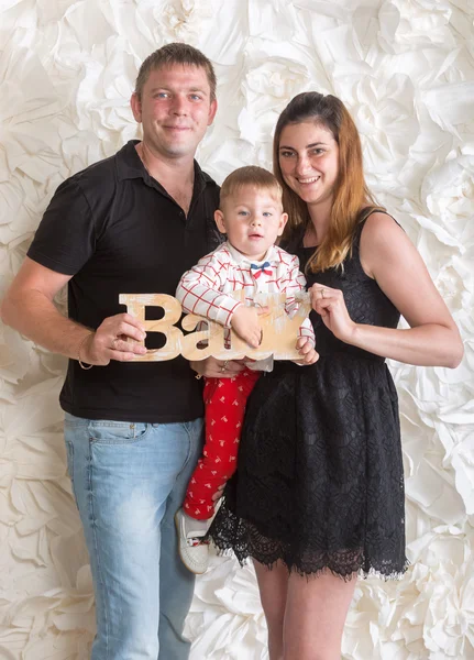 Retrato de familia feliz posando con el bebé hijo en el estudio y sostener —  Fotos de Stock