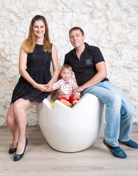 Família feliz com menino posando no estúdio. Menino sentado em deco — Fotografia de Stock