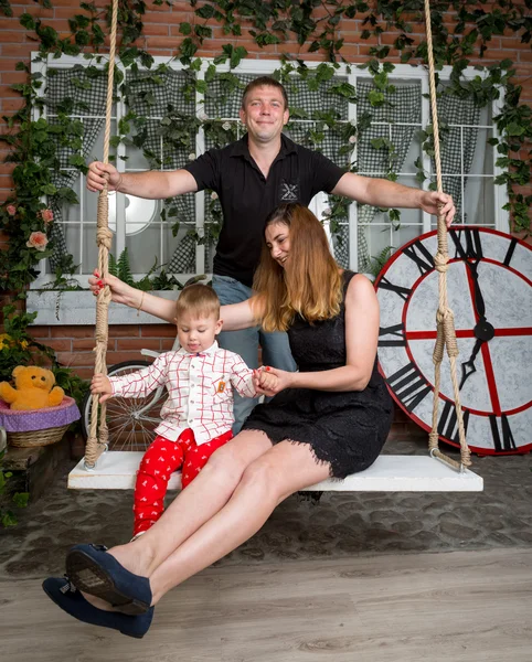 Homem balançando sua esposa e bebê filho no teetering bordo no estúdio — Fotografia de Stock