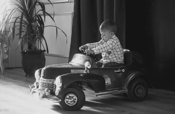 Czarno-biały obraz z 1 roku życia chłopiec jazda konna duża zabawka samochód — Zdjęcie stockowe