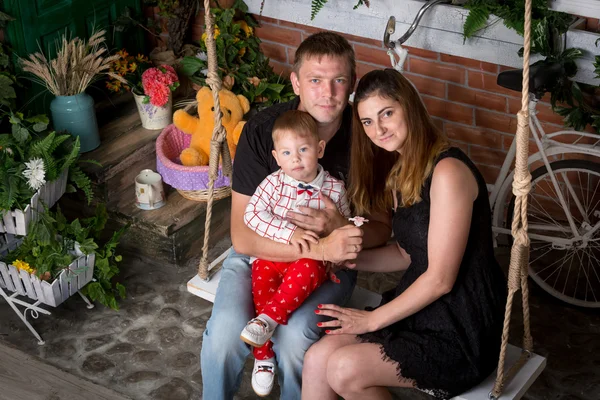Portrait de famille heureuse avec bébé garçon posant sur swing au studio — Photo