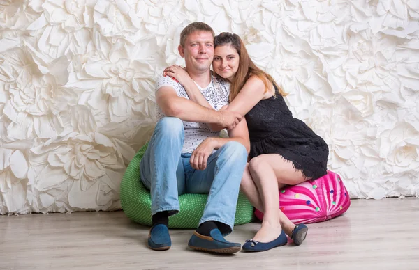 Pareja feliz enamorada sentada en bolsas de frijoles en el estudio —  Fotos de Stock