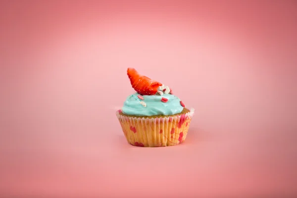 Cupcake com creme azul e morango fresco sobre backgroun rosa — Fotografia de Stock