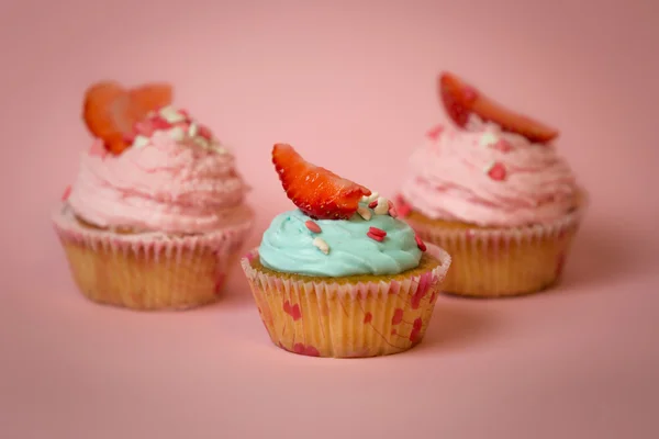 Toned foto de três cupcakes decorados sobre fundo rosa — Fotografia de Stock