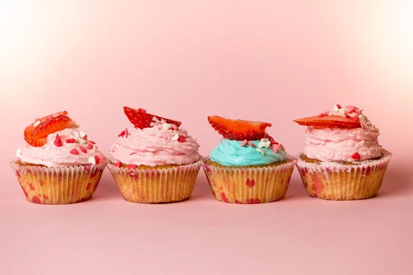 Primer plano de cupcakes de colores con espolvoreos y fresas frescas — Foto de Stock