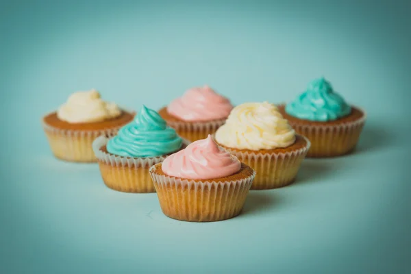 Foto tonificada de cupcakes coloridos recién horneados sobre fondo azul — Foto de Stock