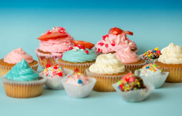 Cupcakes coloridos caseiros e doces no fundo azul — Fotografia de Stock