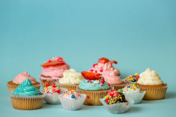 Cupcakes coloridos con fresa y caramelos con espolvoreos — Foto de Stock