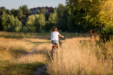 Gün batımında toprak yol üzerinde çayır adlı kadın binicilik bisiklet