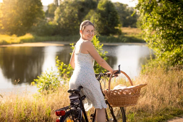 Toned portrait of woman in dress sitting on bike at the lake — Stock Photo, Image