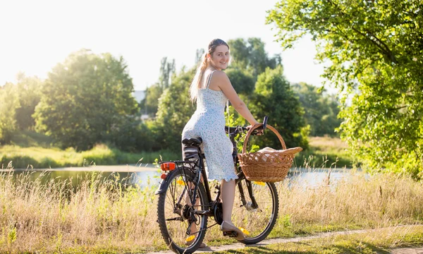 Beautiful woman in dress riding a bicycle by the river at hot su — Stock Photo, Image