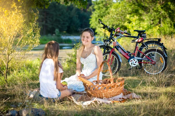 Family having picnic by the river. Smiling mother and daughter l — Stock Photo, Image
