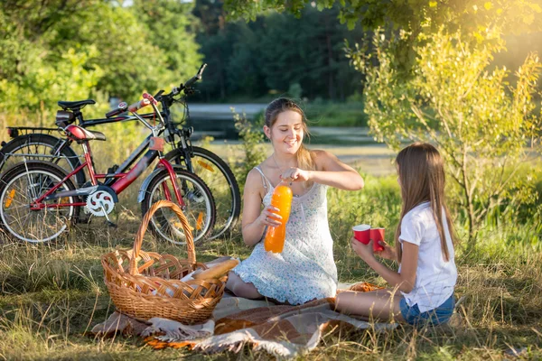 Young woman having picnic by the river with 10 years old daughte — Stock Photo, Image